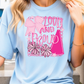 A woman wearing a light blue t-shirt with a graphic design featuring a pink cheerleader, flowers, and the text "LOUD AND PROUD".