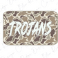 A rectangular sticker or decal with the word "TROJANS" written in a stylized, graffiti-like font against a camouflage pattern background.
