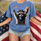 A person wearing a blue t-shirt with a raccoon graphic and holding an American flag.