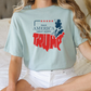 a woman sitting on a bed wearing a trump t - shirt