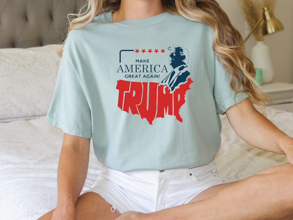 a woman sitting on a bed wearing a trump t - shirt