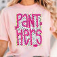 A woman wearing a pink t-shirt with the text "PANT HERS" printed on it.