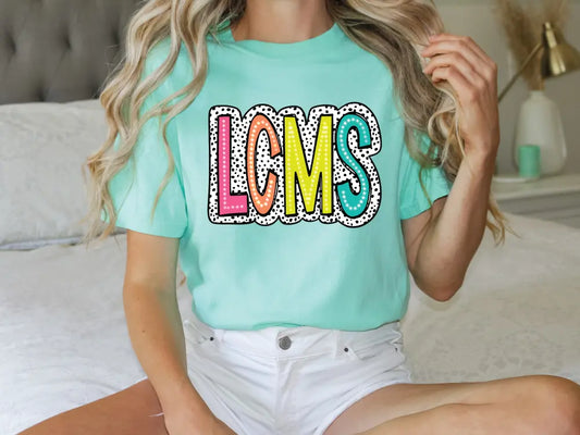 a woman sitting on a bed wearing a t - shirt that says loms