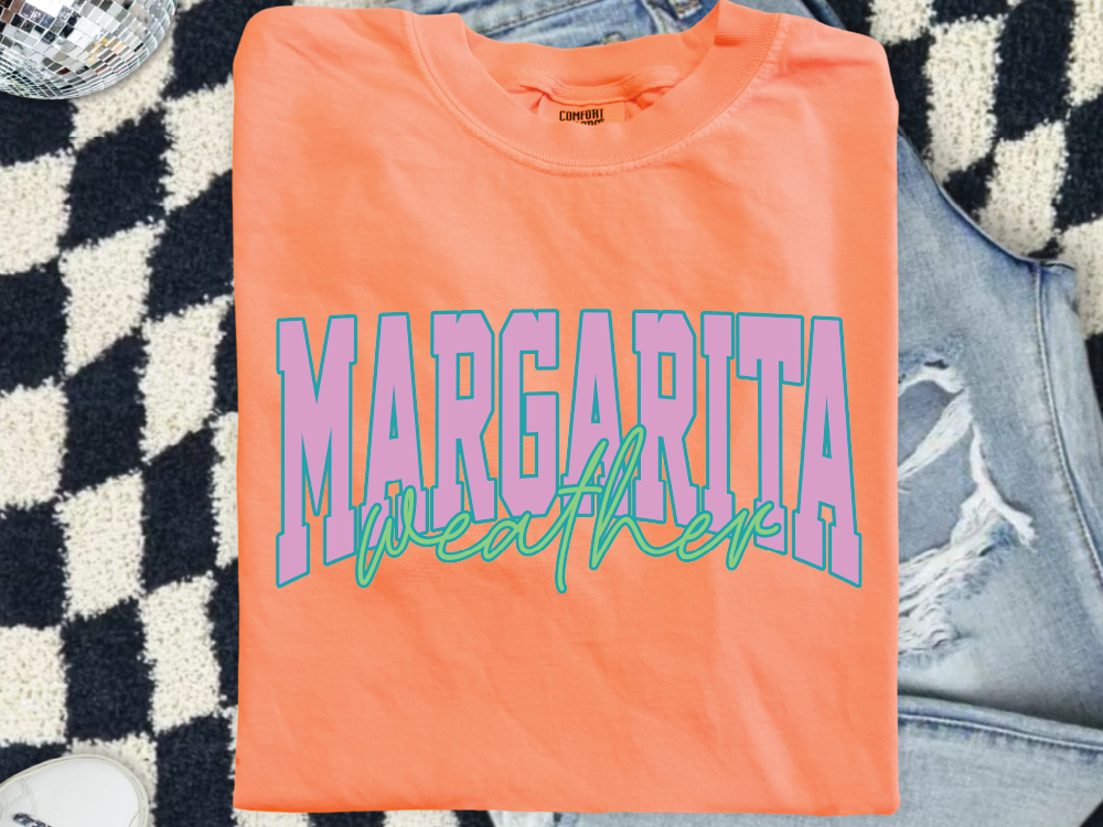 a bright orange t-shirt with the word "MARGARITA" printed on it, along with some distressed denim jeans.