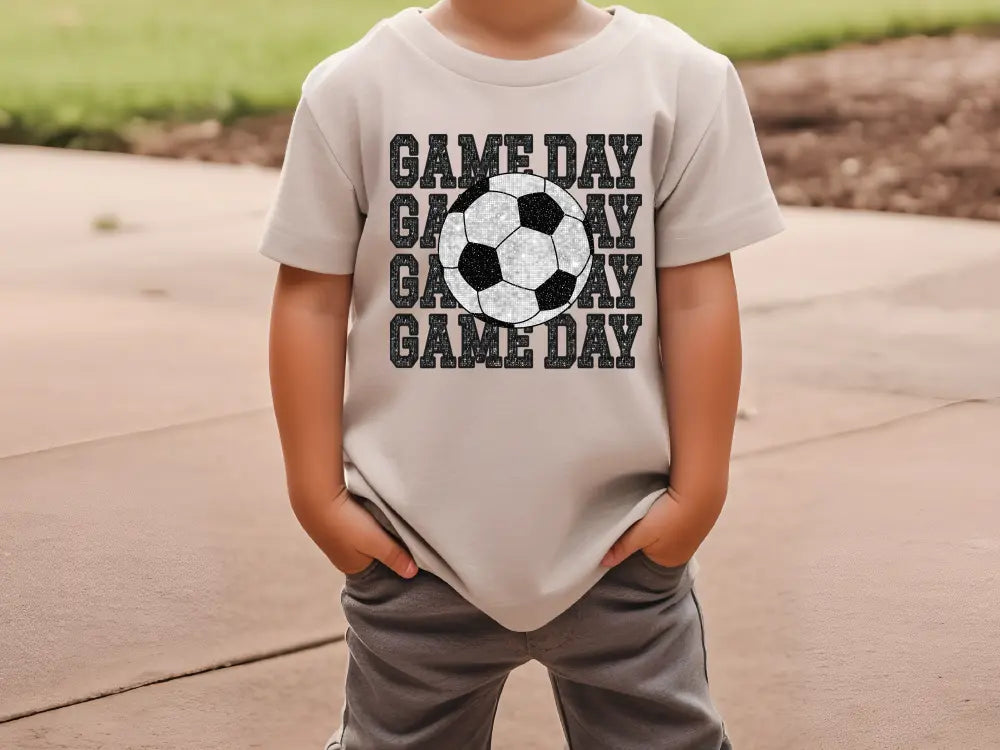 a young boy wearing a t - shirt with a soccer ball on it