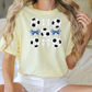 a woman sitting on a bed wearing a yellow shirt with soccer balls on it