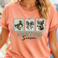 A woman wearing a peach-colored t-shirt with a graphic design featuring a duck, deer, and bow tie, along with the text "Hunting Season".