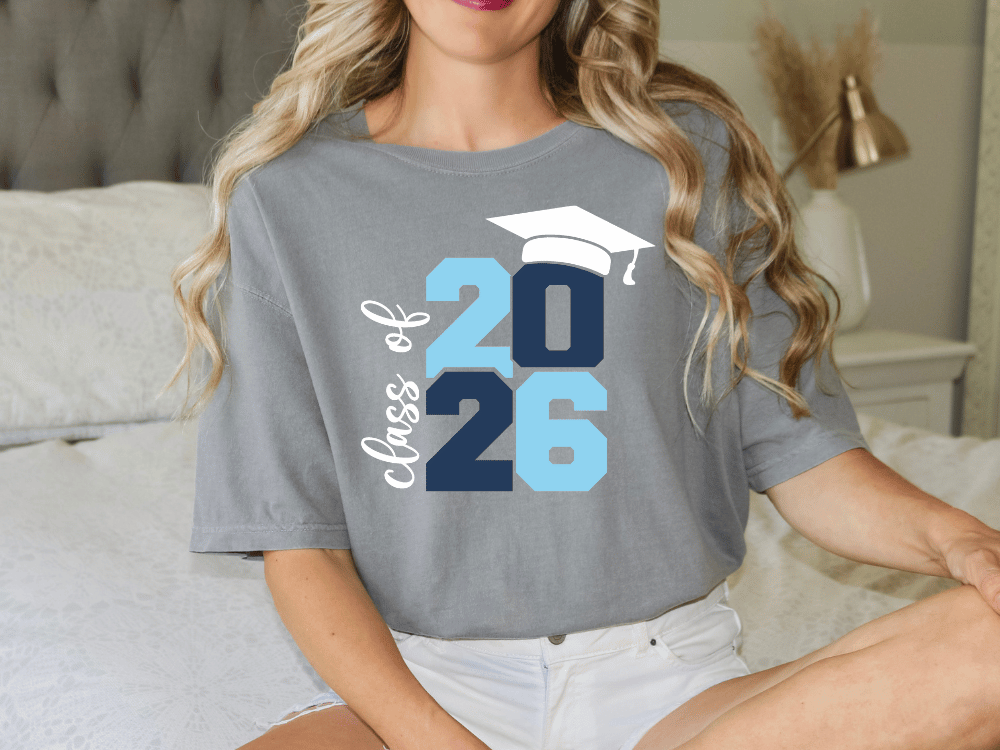A woman wearing a gray t-shirt with a graphic design that says "Class of 26" and a graduation cap.