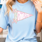A woman wearing a light blue t-shirt with a pink and white design on it.
