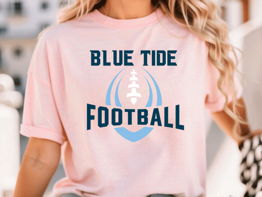 A woman wearing a pink t-shirt with the text "BLUE TIDE FOOTBALL" printed on it.