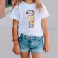 a little girl wearing a white shirt and denim shorts