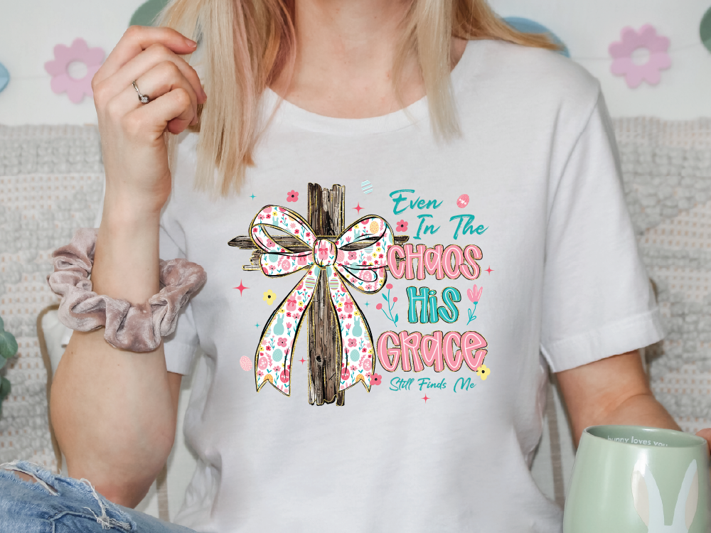 A woman wearing a white t-shirt with a colorful graphic design and text printed on it.