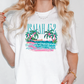 A woman wearing a white t-shirt with a graphic design featuring palm trees and a beach scene.