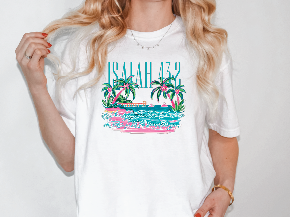 A woman wearing a white t-shirt with a graphic design featuring palm trees and a beach scene.