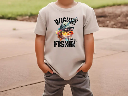 a young boy wearing a white shirt with a fish on it