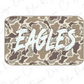 A camouflage-patterned object with the word "EAGLES" written on it in a stylized, graffiti-like font.