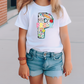 a little girl wearing a white shirt and denim shorts