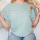 A woman wearing a light green t-shirt with the text "walking by faith, tripping constantly" printed on it.