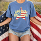 A person wearing a blue t-shirt with a star design and the text "AMERICA HALLOWEAH" is holding an American flag.
