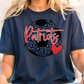 A person wearing a navy blue t-shirt with a graphic design featuring a soccer ball and the word "Patriots" written on it.