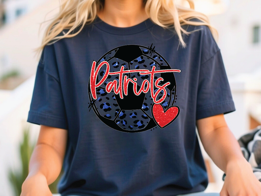 A person wearing a navy blue t-shirt with a graphic design featuring a soccer ball and the word "Patriots" written on it.