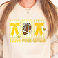 A woman wearing a white sweatshirt with a graphic design featuring a football, yellow bows, and the text "TOUGH DOWN SEASON".