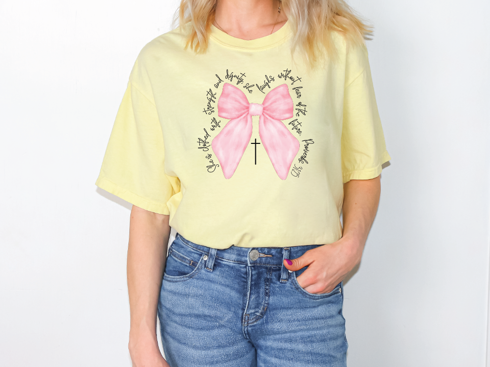 a woman wearing a yellow shirt with a pink bow on it