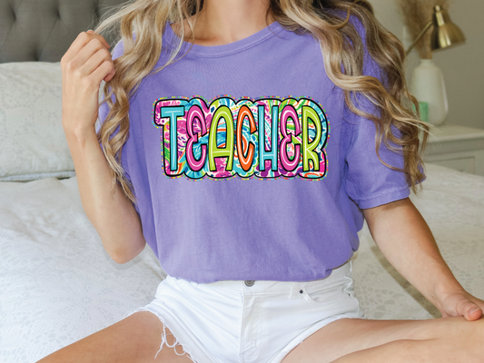 a woman sitting on a bed wearing a purple teacher shirt