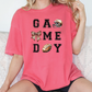 a woman sitting on a couch wearing a game day shirt