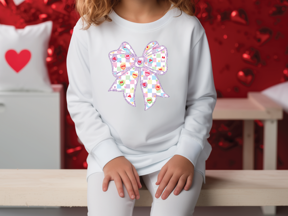 a little girl sitting on a bench with a bow on her shirt