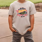 a young boy standing on a sidewalk wearing a t - shirt