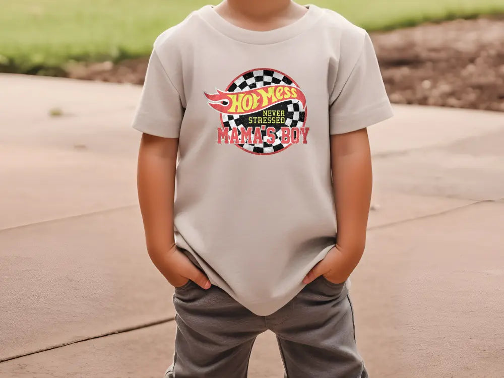 a young boy standing on a sidewalk wearing a t - shirt