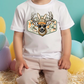 A child wearing a white t-shirt with a graphic of a deer wearing sunglasses and a hat.