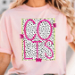 A woman wearing a pink t-shirt with a graphic design featuring the word "COLTS" in pink and black, with a polka dot pattern.