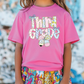 a little girl wearing a pink shirt and colorful shorts