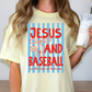 A woman wearing a yellow t-shirt with a graphic design that says "JESUS AND BASEBALL run the bases set before you".