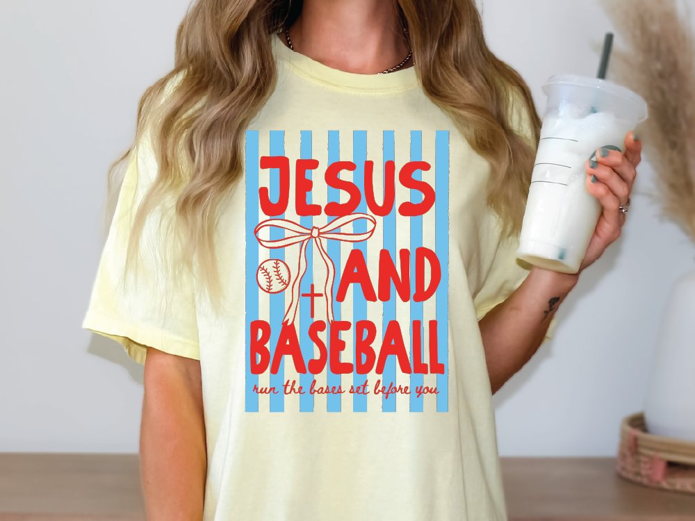 A woman wearing a yellow t-shirt with a graphic design that says "JESUS AND BASEBALL run the bases set before you".