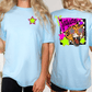 A woman wearing a light blue t-shirt with a graphic design on the back, including a leopard and colorful stars.