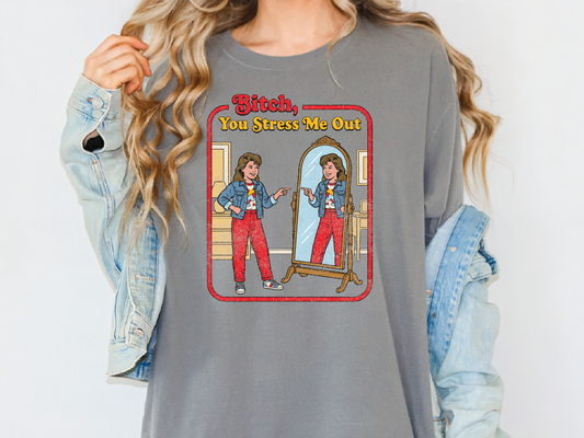 A woman wearing a gray t-shirt with a graphic design depicting two women in a mirror, one of whom is holding a sign that says "Bitch, You Stress Me Out".