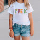 a little girl standing on a sidewalk wearing a t - shirt that says prek