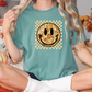 a woman sitting on a bed wearing a t - shirt with a smiley face on