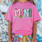 a little girl wearing a pink shirt with a smiley face