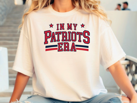 A person wearing a white t-shirt with the text "IN MY PATRIOTS ERA" printed on it.