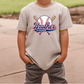 A child wearing a white t-shirt with a baseball graphic and the text "Brother of the Broccoli" printed on it.