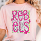 A woman wearing a pink t-shirt with the text "REBELS" printed on it.