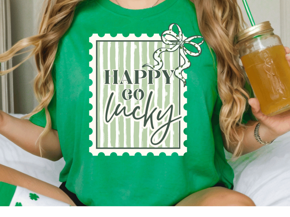 A person wearing a green t-shirt with the text "HAPPY go lucky" printed on it, holding a glass of what appears to be a yellow beverage.