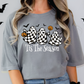 A woman wearing a gray t-shirt with a graphic design featuring three ghostly figures and the text "Tis The Season" printed on it.