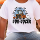A white t-shirt with a Halloween-themed graphic design featuring a tractor, a ghost, and a pumpkin.