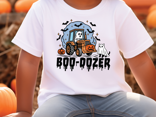 A white t-shirt with a Halloween-themed graphic design featuring a tractor, a ghost, and a pumpkin.