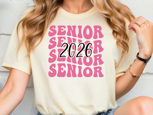 A woman wearing a white t-shirt with pink text that says "SENIOR SENIOR SENIOR SENIOR 2026".